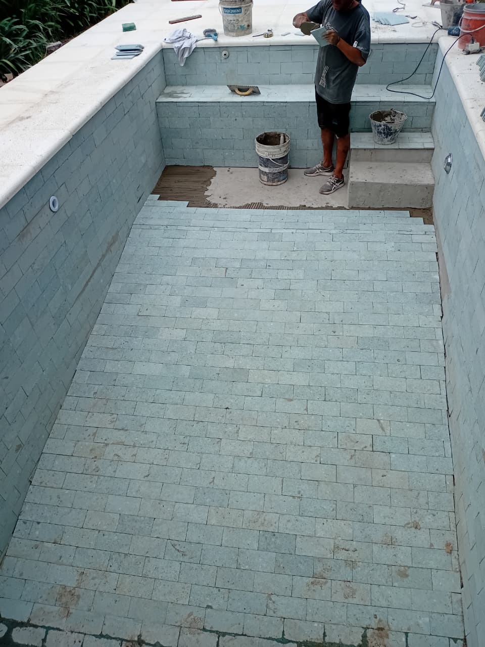 Trabajador de JM Piletas colocando cerámicos en pileta de hormigón